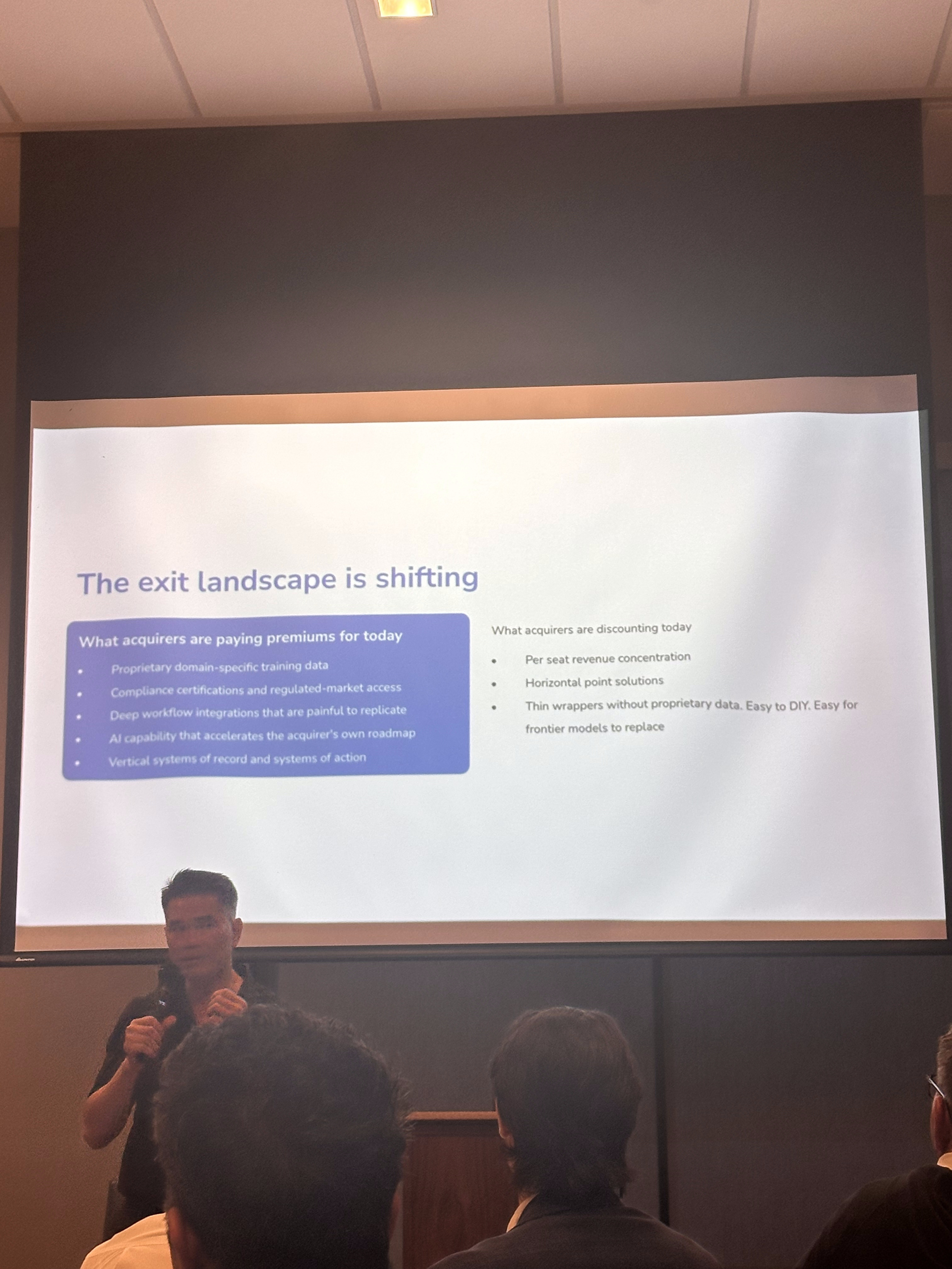 John Eng presents the 'Exit landscape is shifting' slide, listing what acquirers pay premiums for versus what they discount.